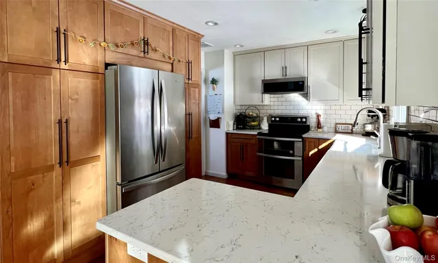 a kitchen with stainless steel appliances granite countertop a refrigerator a stove and a sink with wooden floor