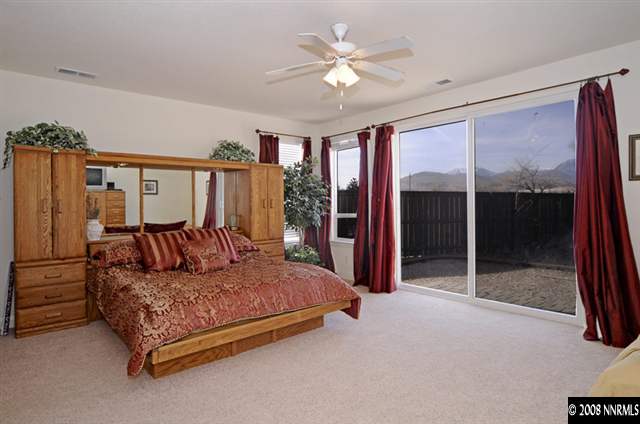14105 Princequillo Court Reno, NV 89521 - Photo 7 of 9 a spacious bedroom with a large bed and a chandelier fan