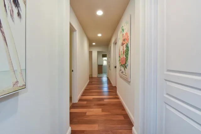 a view of a hallway with wooden floor and staircase