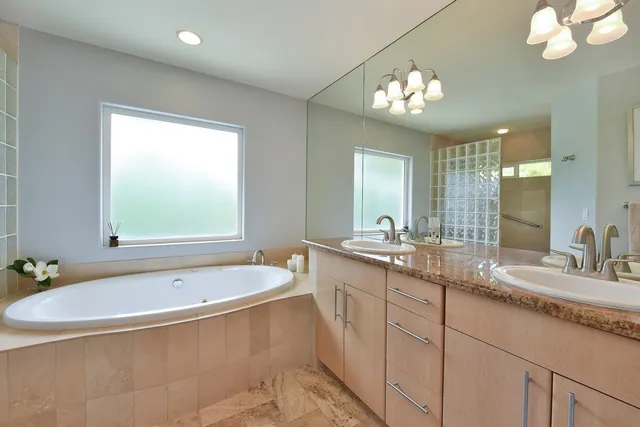 a bathroom with a tub a double vanity sink and a mirror