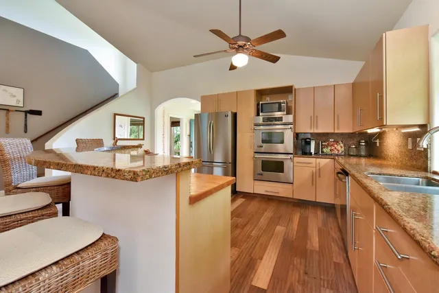 a kitchen with stainless steel appliances kitchen island granite countertop a stove a sink and a refrigerator
