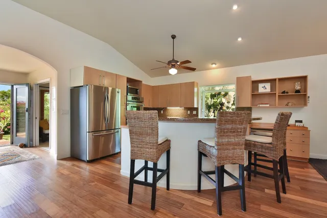 a kitchen with stainless steel appliances a dining table chairs refrigerator and sink