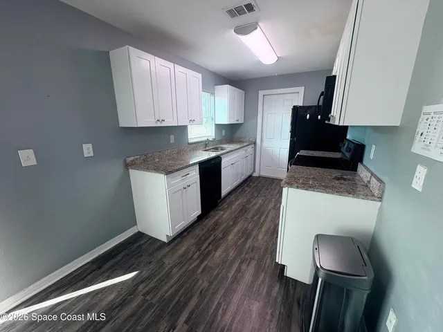 a kitchen with granite countertop wooden floors and white stainless steel appliances