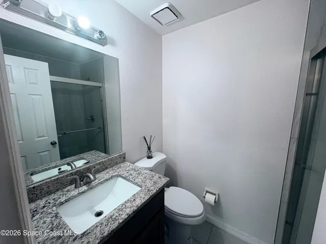 a bathroom with a granite countertop sink a toilet and a mirror