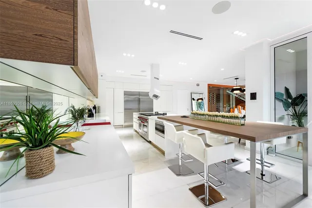 a kitchen with stainless steel appliances kitchen island granite countertop a table chairs in it and wooden floor