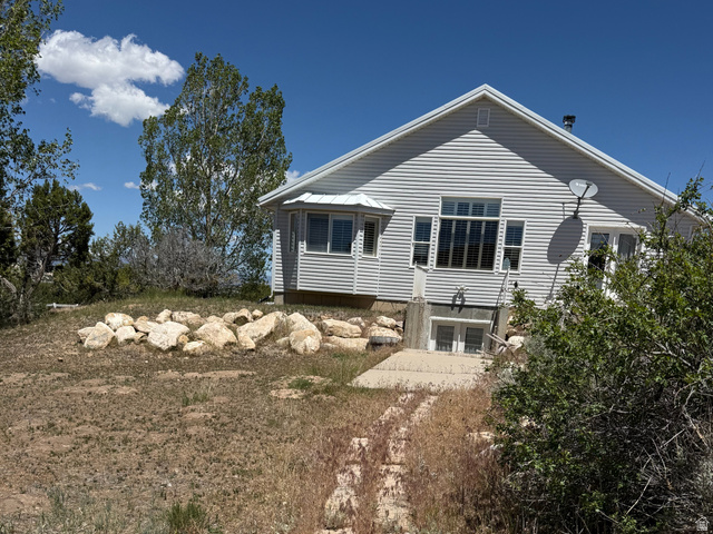 10000 North 6730th East Spring City, UT 84662 - Photo 27 of 31 Gray siding residence featuring a bay window, multiple large windows, and a lower-level double door entry