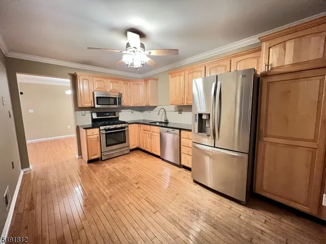 a kitchen with granite countertop stainless steel appliances a refrigerator cabinets and wooden floor