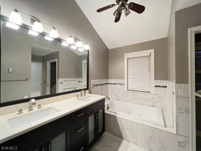 a bathroom with a double vanity sink a large mirror and a bathtub