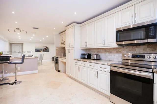 a kitchen with granite countertop white cabinets white stainless steel appliances and sink