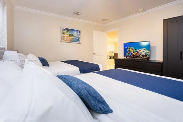 a bedroom with two beds and a flat screen tv