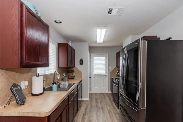 a kitchen with stainless steel appliances granite countertop a refrigerator a stove and a sink with wooden floors