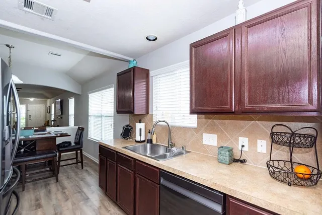 a kitchen with granite countertop wooden cabinets a sink and dishwasher a stove with wooden floor