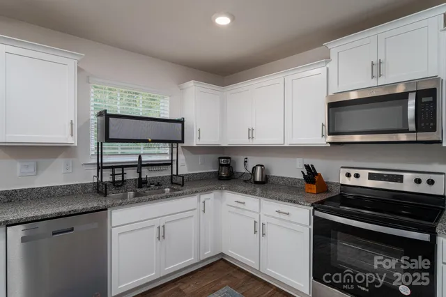 a kitchen with stainless steel appliances white cabinets and a stove top oven