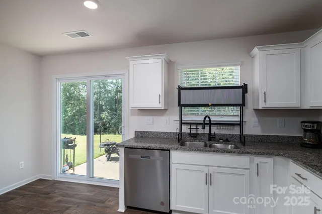 a kitchen with stainless steel appliances granite countertop a sink a stove a window and cabinets