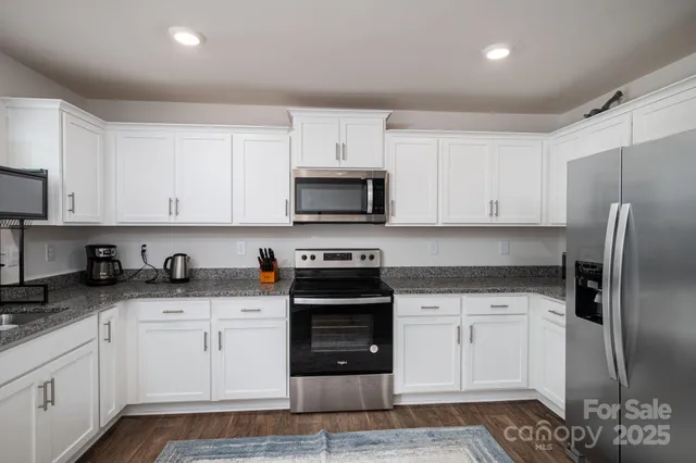 a kitchen with granite countertop white cabinets and stainless steel appliances