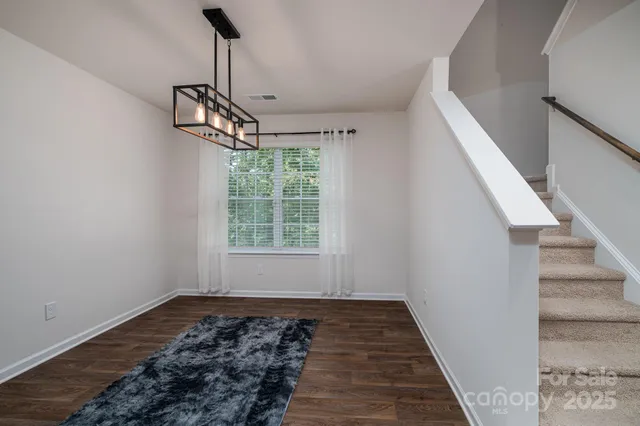 a view of a hallway with wooden floor and chandelier