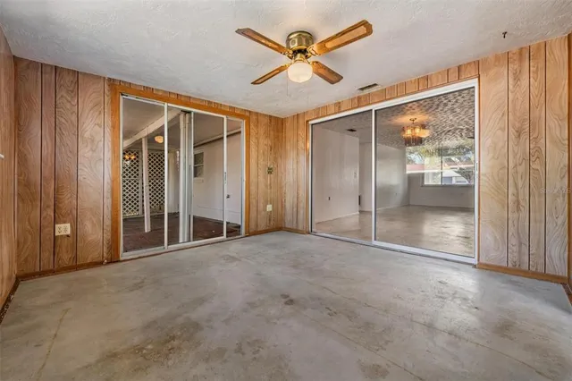 a view of a livingroom with a chandelier fan and windows