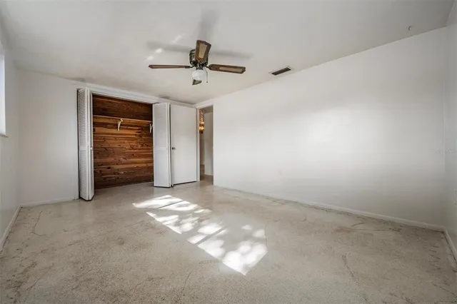 an empty room with windows and fan