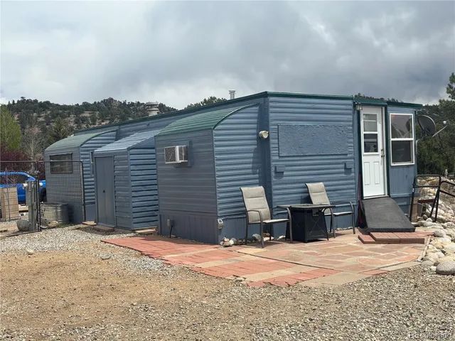 a backyard of a house with large trees and wooden fence