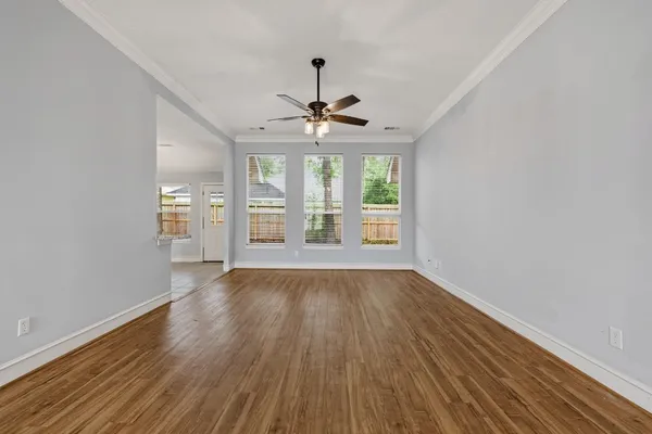 an empty room with wooden floor and windows