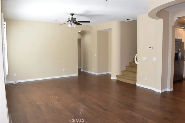 an empty room with wooden floor and a ceiling fan
