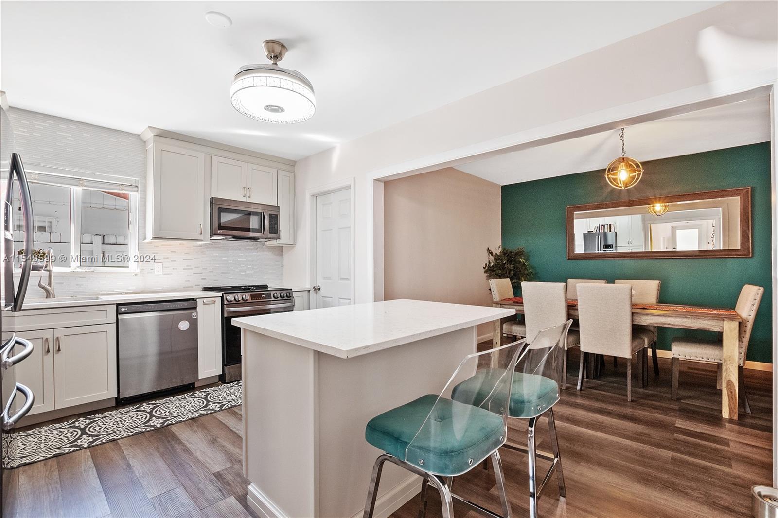 5819 Southwest 4th Street Miami, FL 33144 - Photo 6 of 27 a open kitchen with stainless steel appliances kitchen island granite countertop a stove a sink a dining table and chairs with wooden floor