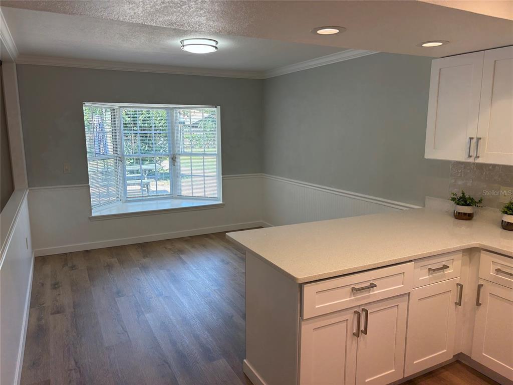 9801 Southeast Sunset Harbor Road Summerfield, FL 34491 - Photo 4 of 37 a view of a kitchen with white cabinets and wooden floor