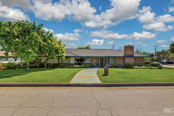 a view of a yard with flower plants and large trees