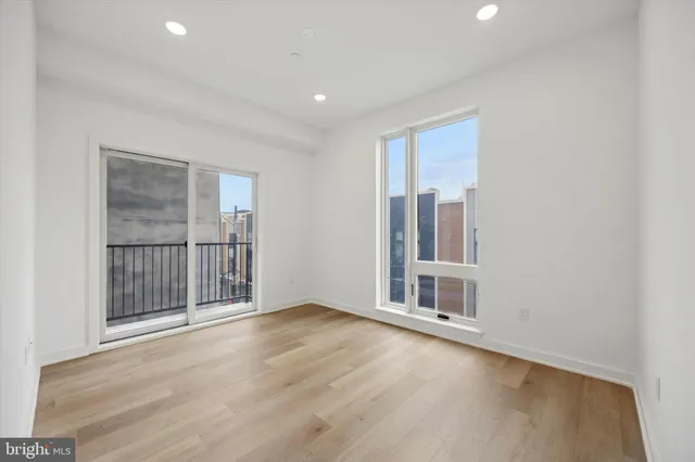 a view of an empty room with wooden floor and fan