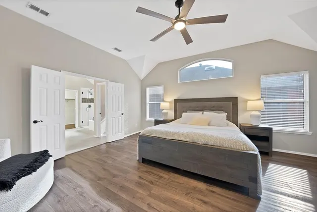 a bedroom with a large bed and wooden floor