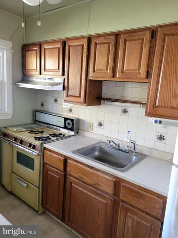 a kitchen with a sink a stove cabinets and a window