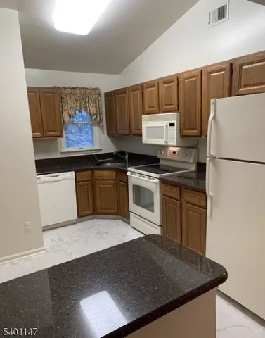 a kitchen with granite countertop a stove a sink dishwasher and a refrigerator