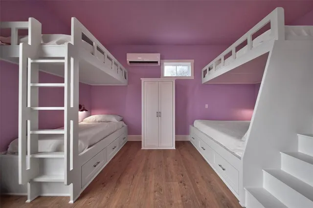 a view of a bedroom with wooden floor and windows