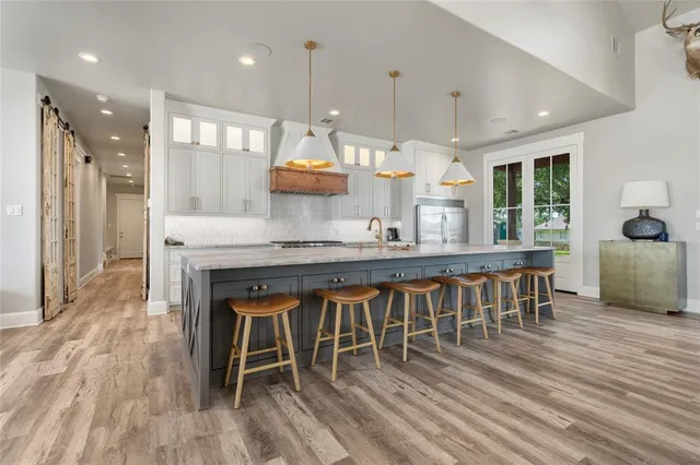 a dining table chairs wooden floor and a large window