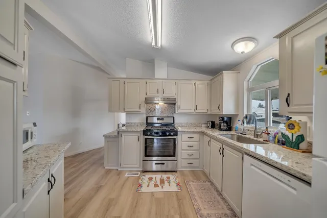 a kitchen with stainless steel appliances granite countertop a stove a sink dishwasher and a refrigerator
