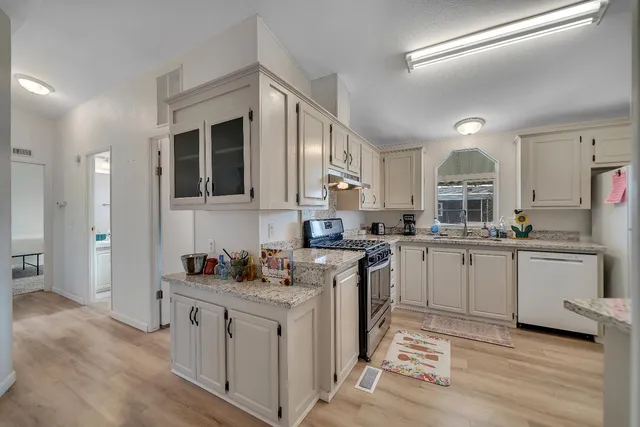 a kitchen with granite countertop a sink stainless steel appliances and cabinets