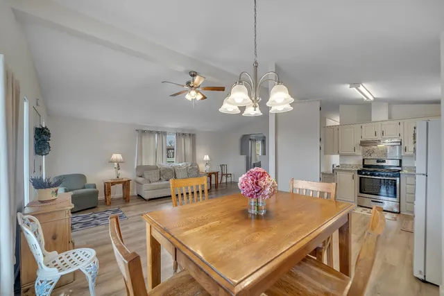 a view of a dining room and livingroom with furniture wooden floor a chandelier