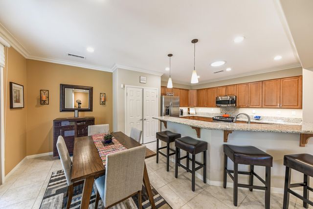 a kitchen with stainless steel appliances granite countertop a dining table chairs and white cabinets