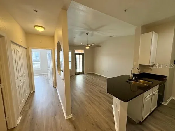 an empty room with wooden floor fan and windows