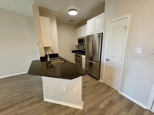 a view of a kitchen with wooden floor and ceiling fan