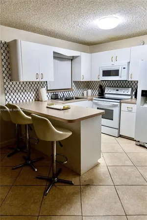 a kitchen with cabinets and chairs