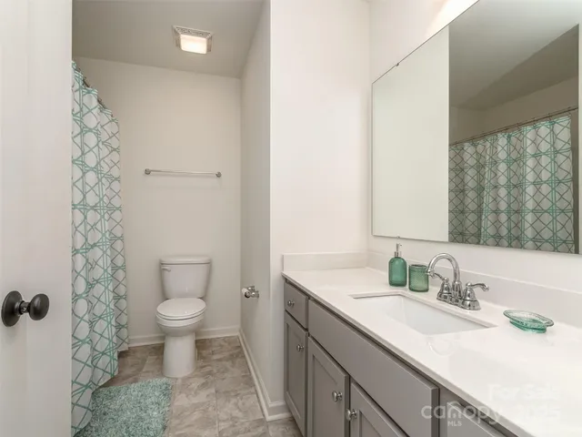 a bathroom with a granite countertop sink a toilet and a mirror