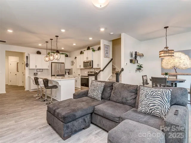 a living room with furniture kitchen view and a chandelier