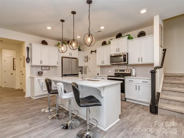 a large kitchen with white cabinets and stainless steel appliances