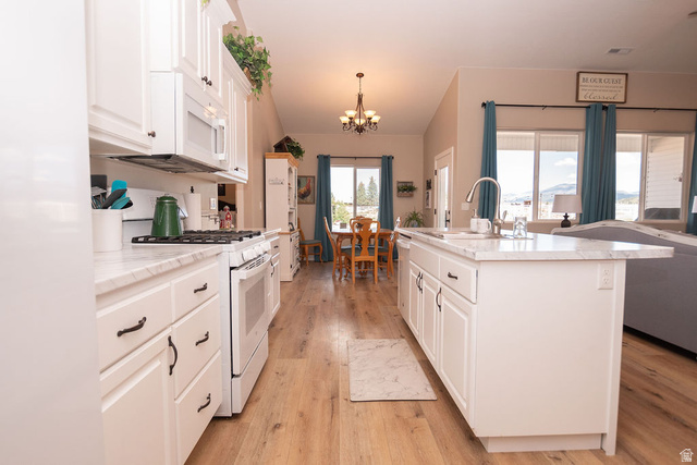 745 East 885 North Beaver, UT 84713 - Photo 19 of 50 Kitchen with white appliances, light countertops, white cabinets, light wood-type flooring, and an island with sink