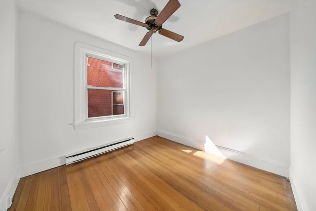 an empty room with wooden floor fan and windows