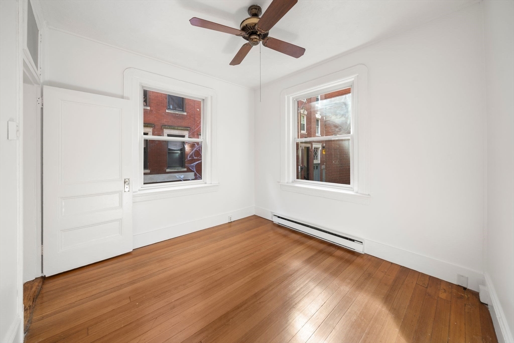 7 Unity Street, Unit 3 Boston, MA 02113 - Photo 15 of 25 an empty room with wooden floor chandelier fan and windows
