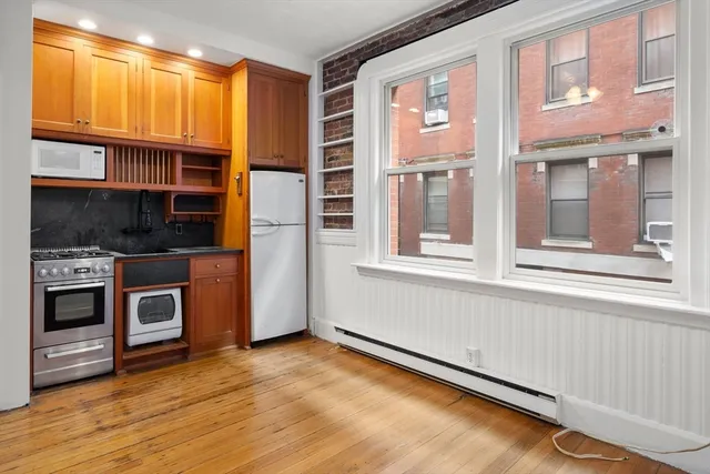 a view of a kitchen with an empty room and wooden floor