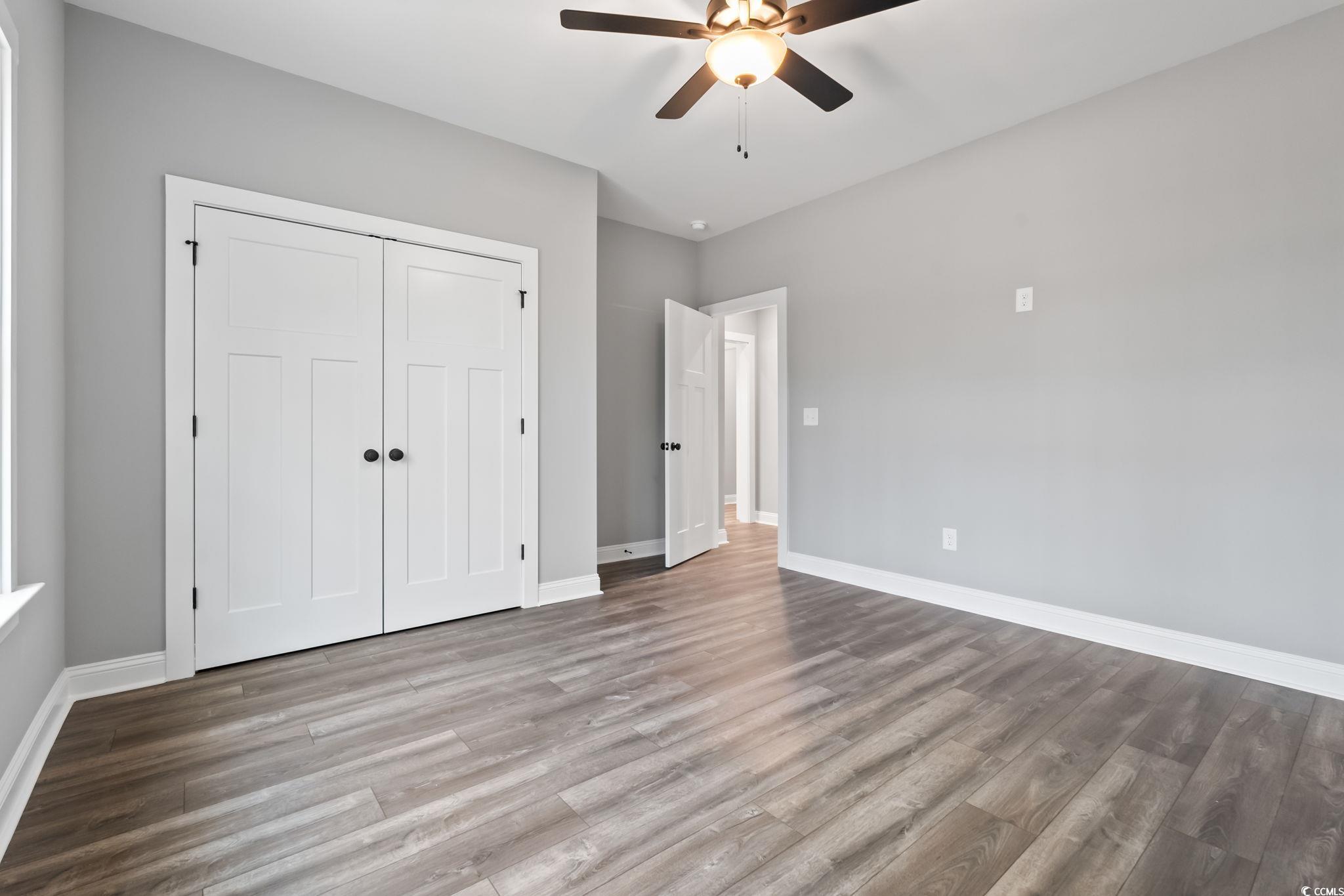 2122 Highway 9 Business Loris, SC 29569 - Photo 29 of 32 Unfurnished bedroom featuring wood finished floors, a closet, and a ceiling fan
