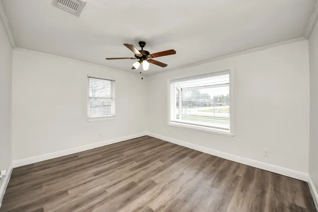 a view of a big room with wooden floor and windows
